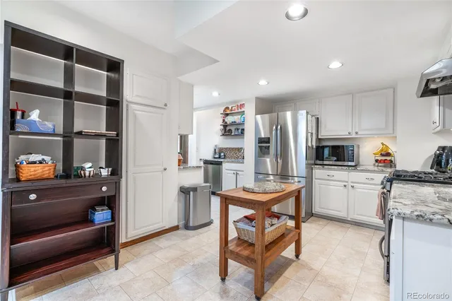 a kitchen with stainless steel appliances kitchen island granite countertop a refrigerator and cabinets