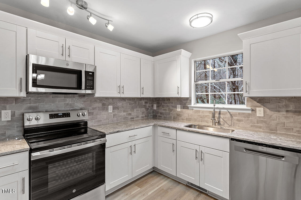 8341 Wynewood Court Raleigh, NC 27616 - Photo 11 of 35 a kitchen with stainless steel appliances granite countertop a sink dishwasher a microwave oven and white cabinets