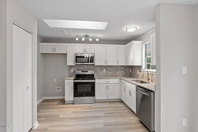 a kitchen with stainless steel appliances granite countertop a stove top oven a sink and a refrigerator