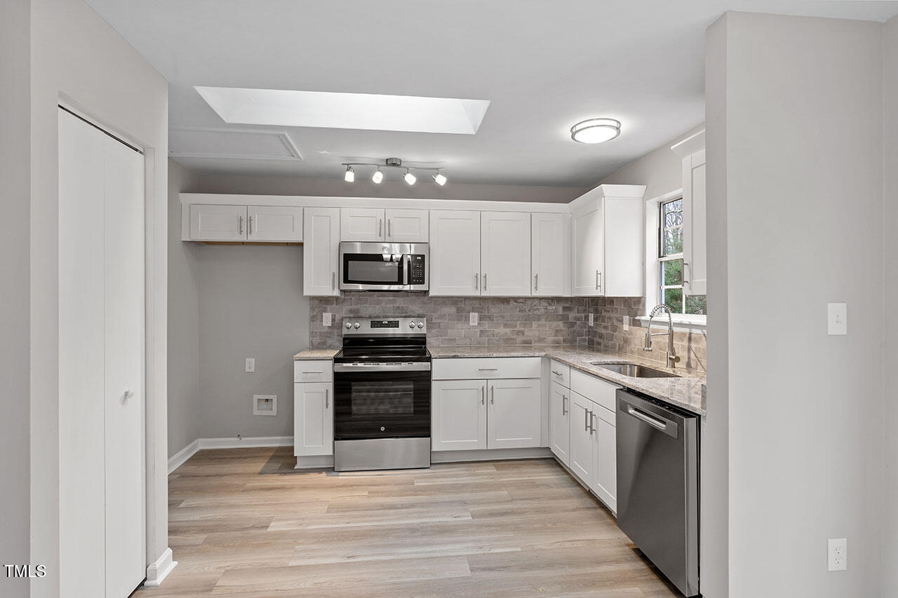 8341 Wynewood Court Raleigh, NC 27616 - Photo 12 of 35 a kitchen with stainless steel appliances granite countertop a stove top oven a sink and a refrigerator