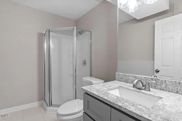 a bathroom with a granite countertop sink a toilet and shower