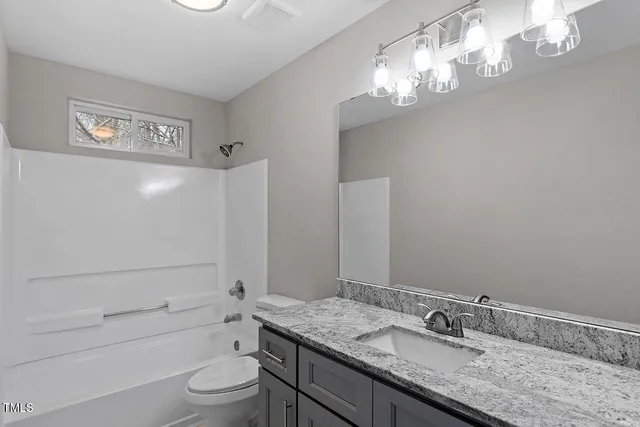a bathroom with a granite countertop sink a toilet and shower