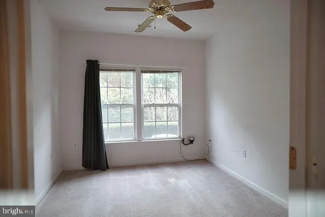 an empty room with a window and a ceiling fan