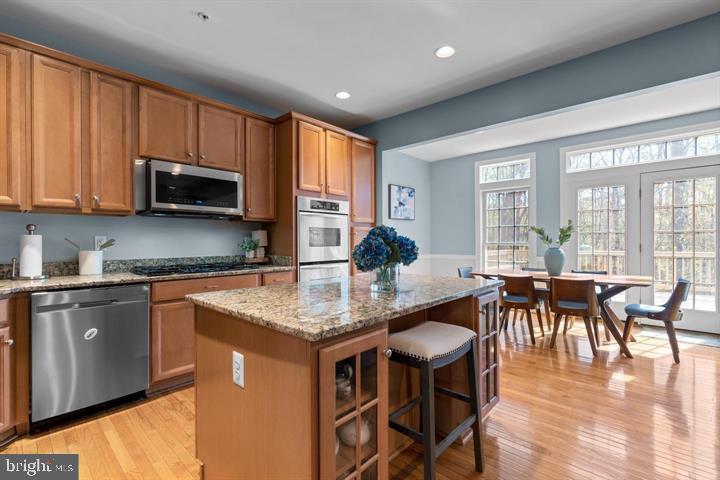 1556 Penzance Way Hanover, MD 21076 - Photo 14 of 40 a kitchen with kitchen island granite countertop wooden floor dining table and stainless steel appliances