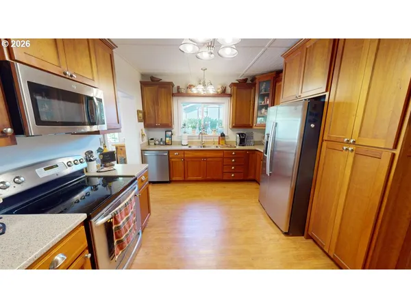 a kitchen with stainless steel appliances granite countertop a refrigerator a stove top oven a sink dishwasher and wooden cabinets