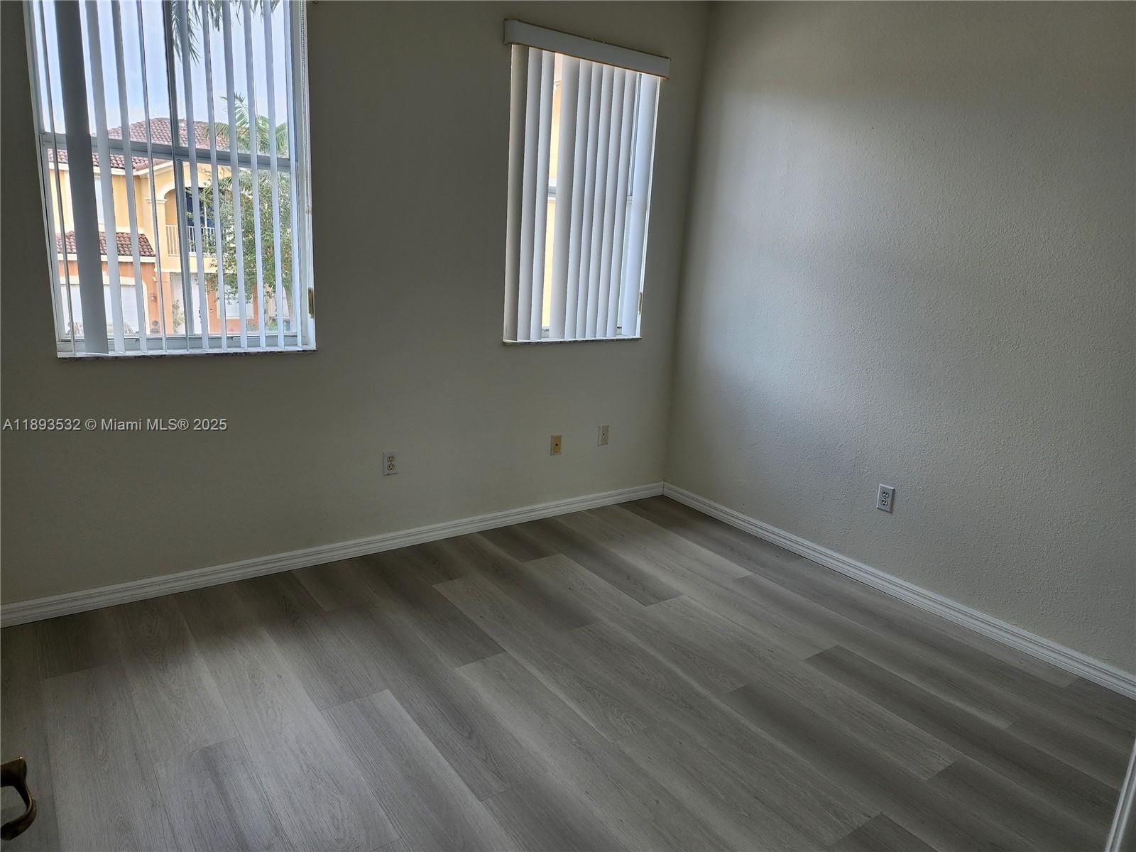 10831 Southwest 240th Lane Homestead, FL 33032 - Photo 21 of 33 an empty room with wooden floor and windows