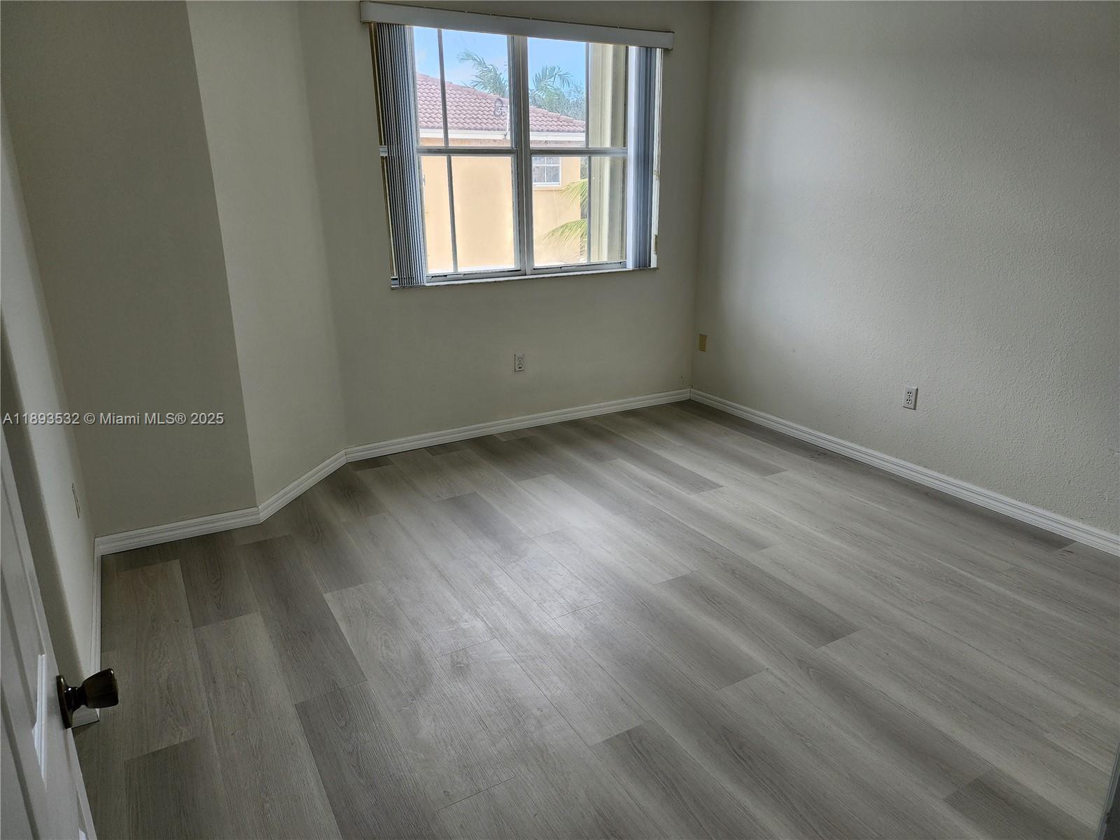 10831 Southwest 240th Lane Homestead, FL 33032 - Photo 22 of 33 an empty room with wooden floor and windows