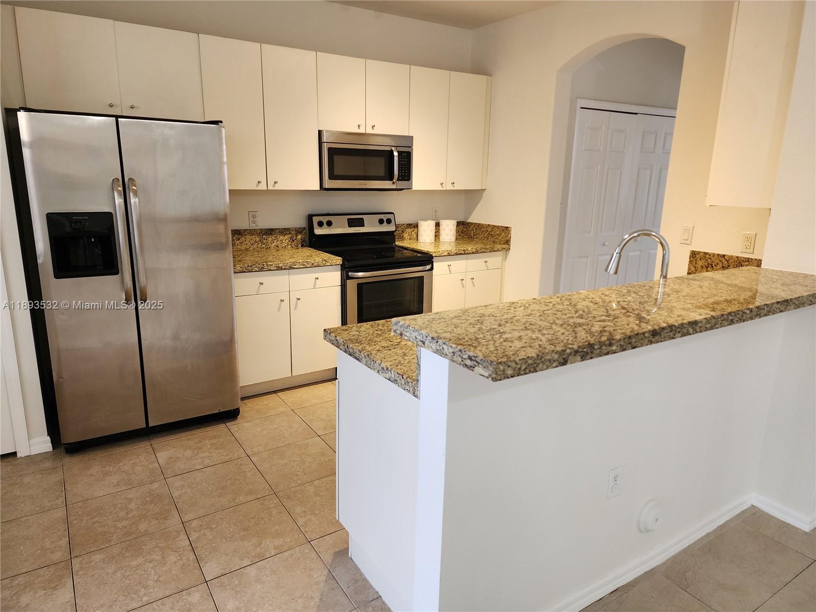 10831 Southwest 240th Lane Homestead, FL 33032 - Photo 6 of 33 a kitchen with granite countertop a refrigerator and a stove top oven