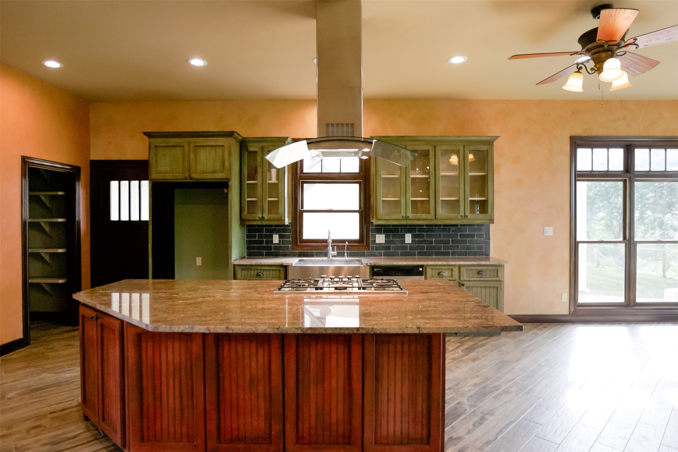3149 Byrd Ranch Road Johnson City, TX 78636 - Photo 8 of 39 Kitchen with green cabinets, glass insert cabinets, island exhaust hood, decorative backsplash, and recessed lighting