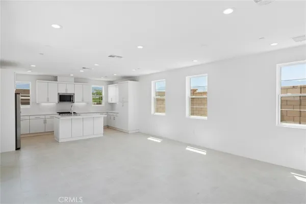 a large white kitchen with kitchen island a sink a center island stainless steel appliances and a window