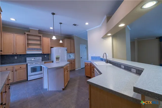 a kitchen with stainless steel appliances granite countertop a sink a stove and a refrigerator