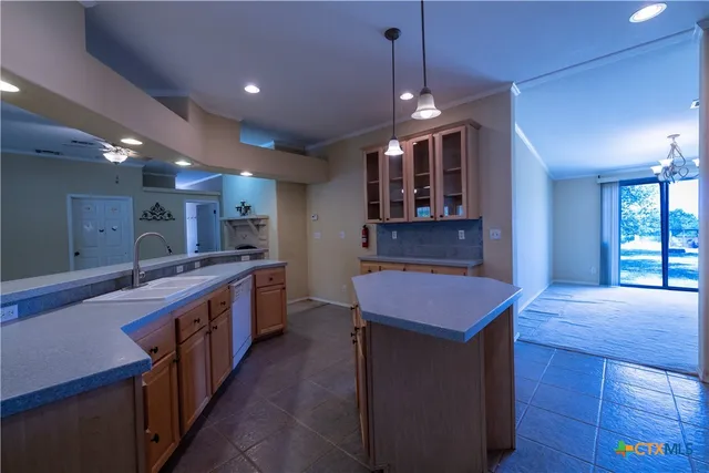 a kitchen with a stove a kitchen island a sink dishwasher a dining table and chairs with wooden floor