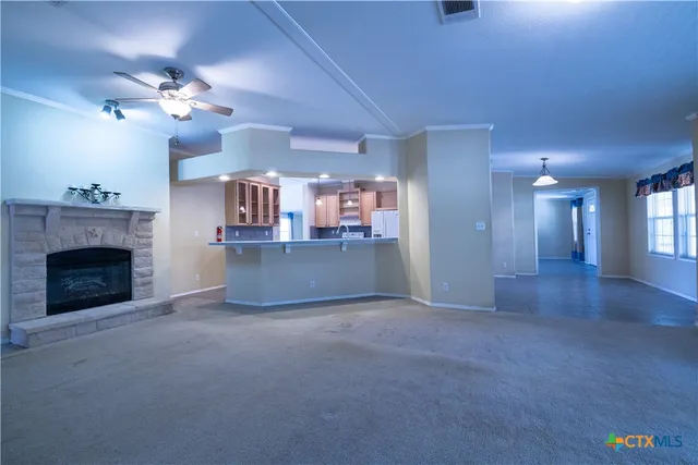 a view of a kitchen with a fireplace a ceiling fan and wooden floor