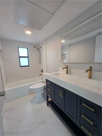 a spacious bathroom with a double vanity sink toilet mirror and bathtub