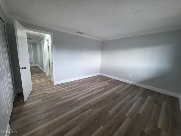 an empty room with wooden floor and a hallway