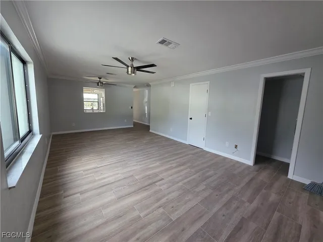 a view of an empty room with wooden floor and a window