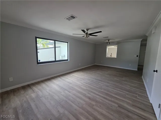 a view of an empty room with a window and wooden floor