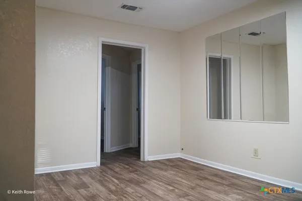 a view of an empty room with wooden floor and closet