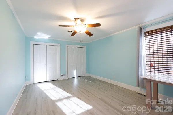 a view of empty room with wooden floor and fan