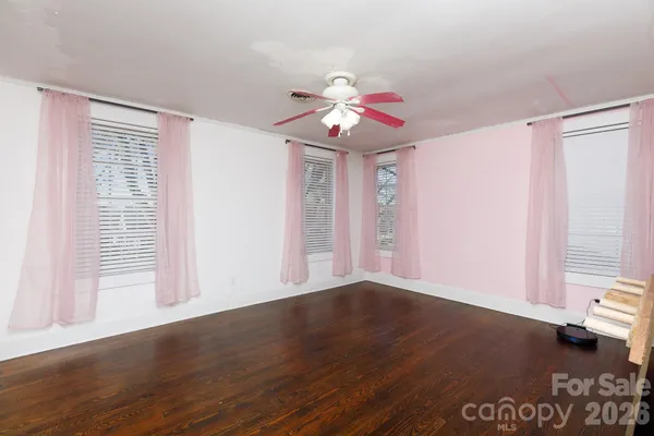 a view of an empty room with a window and wooden floor