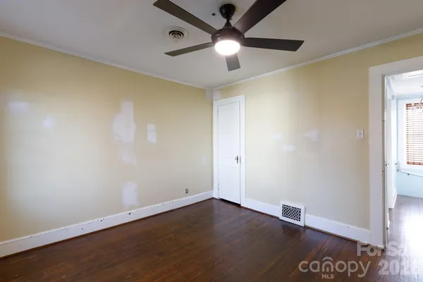 an empty room with wooden floor and ceiling fan