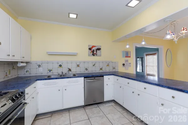 a large white kitchen with a sink and dishwasher with white cabinets