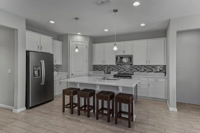 a kitchen with stainless steel appliances granite countertop a table chairs sink refrigerator and cabinets