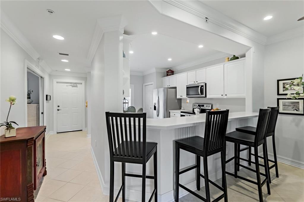 9128 Michael Circle, Unit 9903 Naples, FL 34113 - Photo 4 of 25 a kitchen with kitchen island wooden cabinets and stainless steel appliances