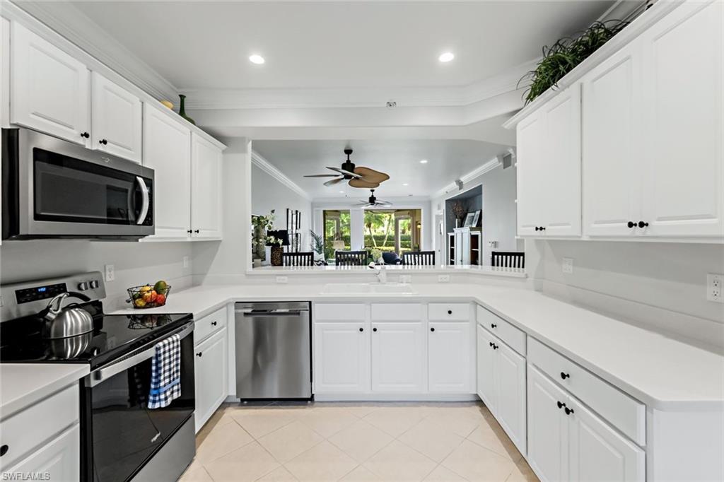 9128 Michael Circle, Unit 9903 Naples, FL 34113 - Photo 8 of 25 a kitchen with kitchen island granite countertop white cabinets white stainless steel appliances with a sink and dishwasher