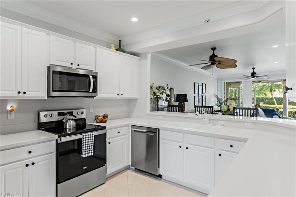 9128 Michael Circle, Unit 9903 Naples, FL 34113 - Photo 9 of 25 a kitchen with white cabinets and black appliances