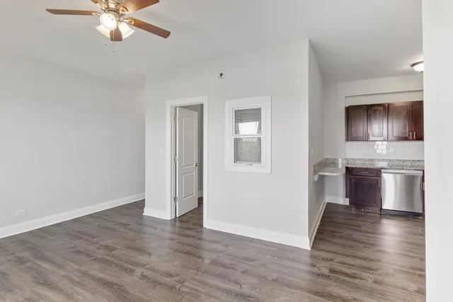 a view of kitchen and empty room with wooden floor