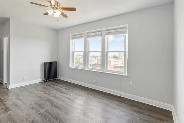 a view of an empty room with a window and wooden floor