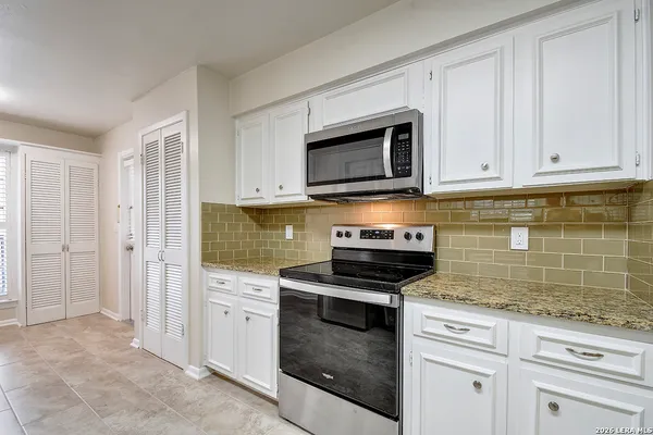 a kitchen with granite countertop white cabinets and stainless steel appliances