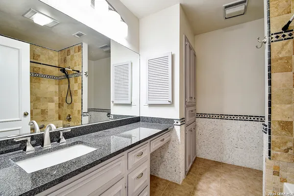 a bathroom with a granite countertop sink mirror and a bathtub