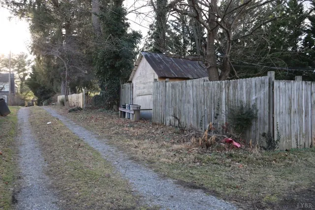 a view of backyard with wooden fence and trees