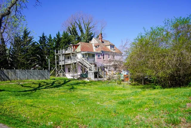 a view of a house with a big yard and potted plants by side of it
