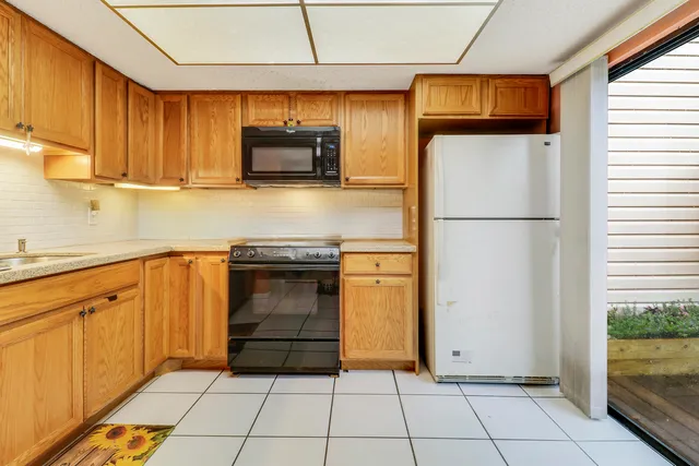 a kitchen with a refrigerator a stove top oven and cabinets
