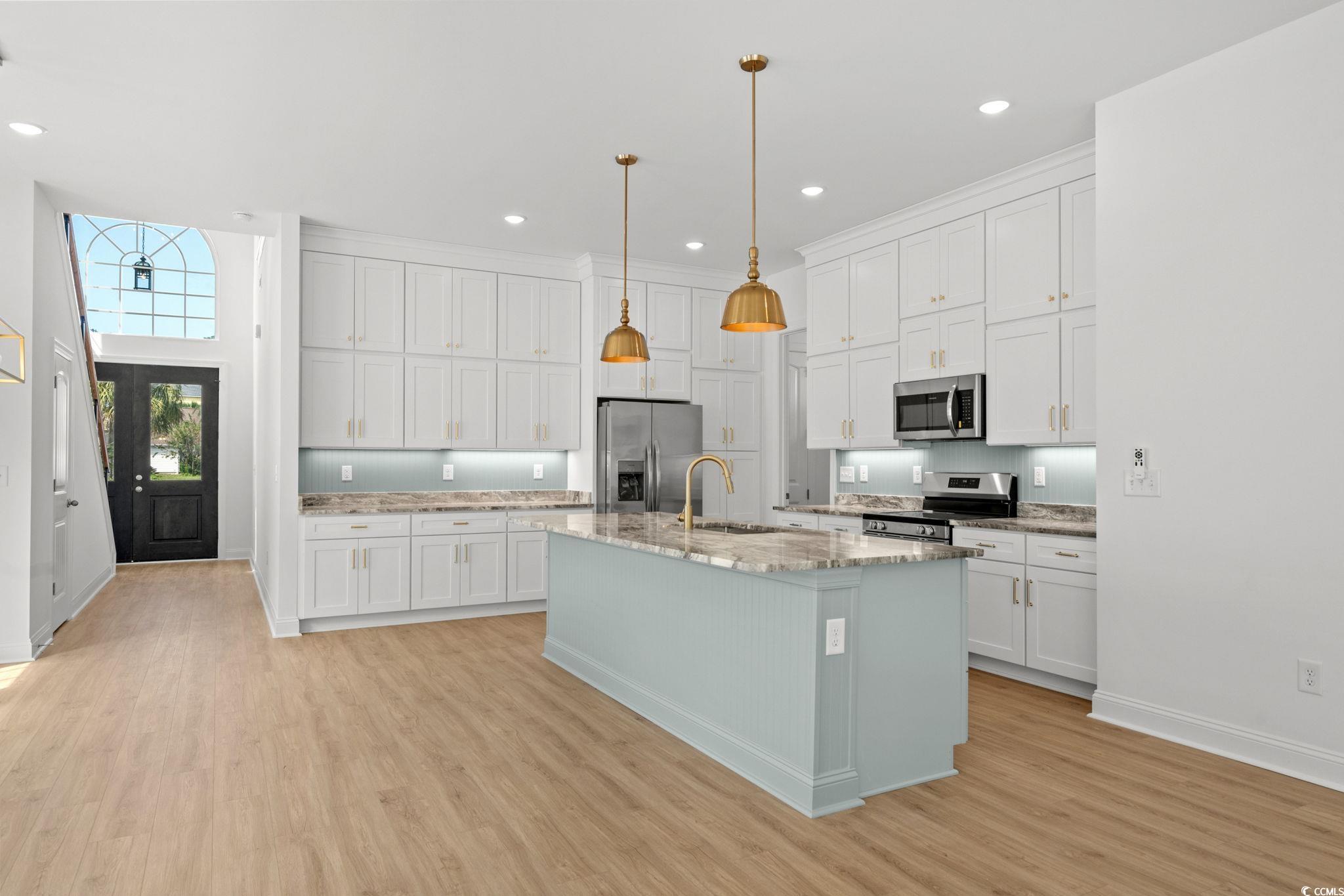 2247 Sand Dunes Drive Myrtle Beach, SC 29577 - Photo 7 of 40 Kitchen featuring white cabinetry, stainless steel appliances, a center island with sink, light wood-style flooring, and pendant lighting