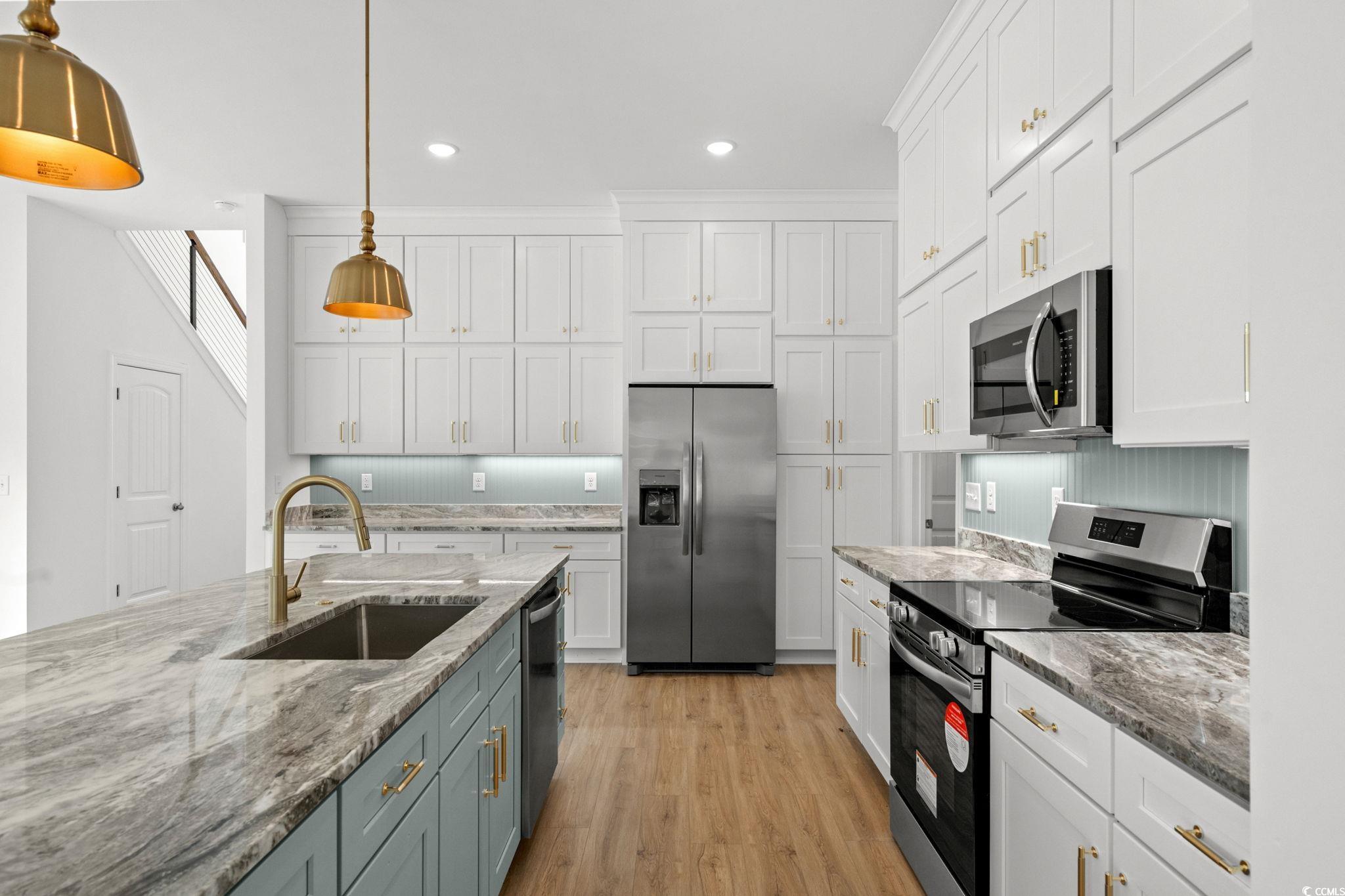 2247 Sand Dunes Drive Myrtle Beach, SC 29577 - Photo 9 of 40 Kitchen featuring appliances with stainless steel finishes, white cabinetry, light stone countertops, light wood-style flooring, and recessed lighting