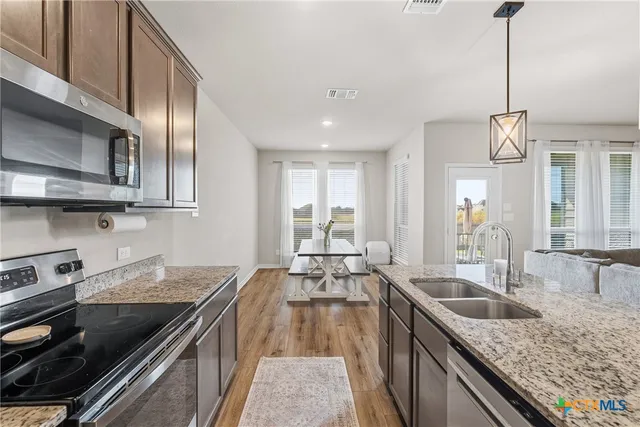 a kitchen with stainless steel appliances granite countertop a sink a stove and a wooden floors