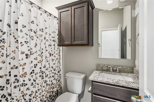 a bathroom with a granite countertop sink toilet and shower