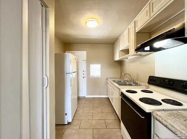 a kitchen with a sink a stove top oven and refrigerator