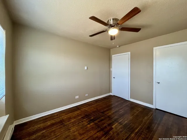 an empty room with wooden floor and ceiling fan