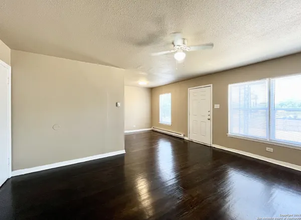 a view of an empty room with wooden floor and a window