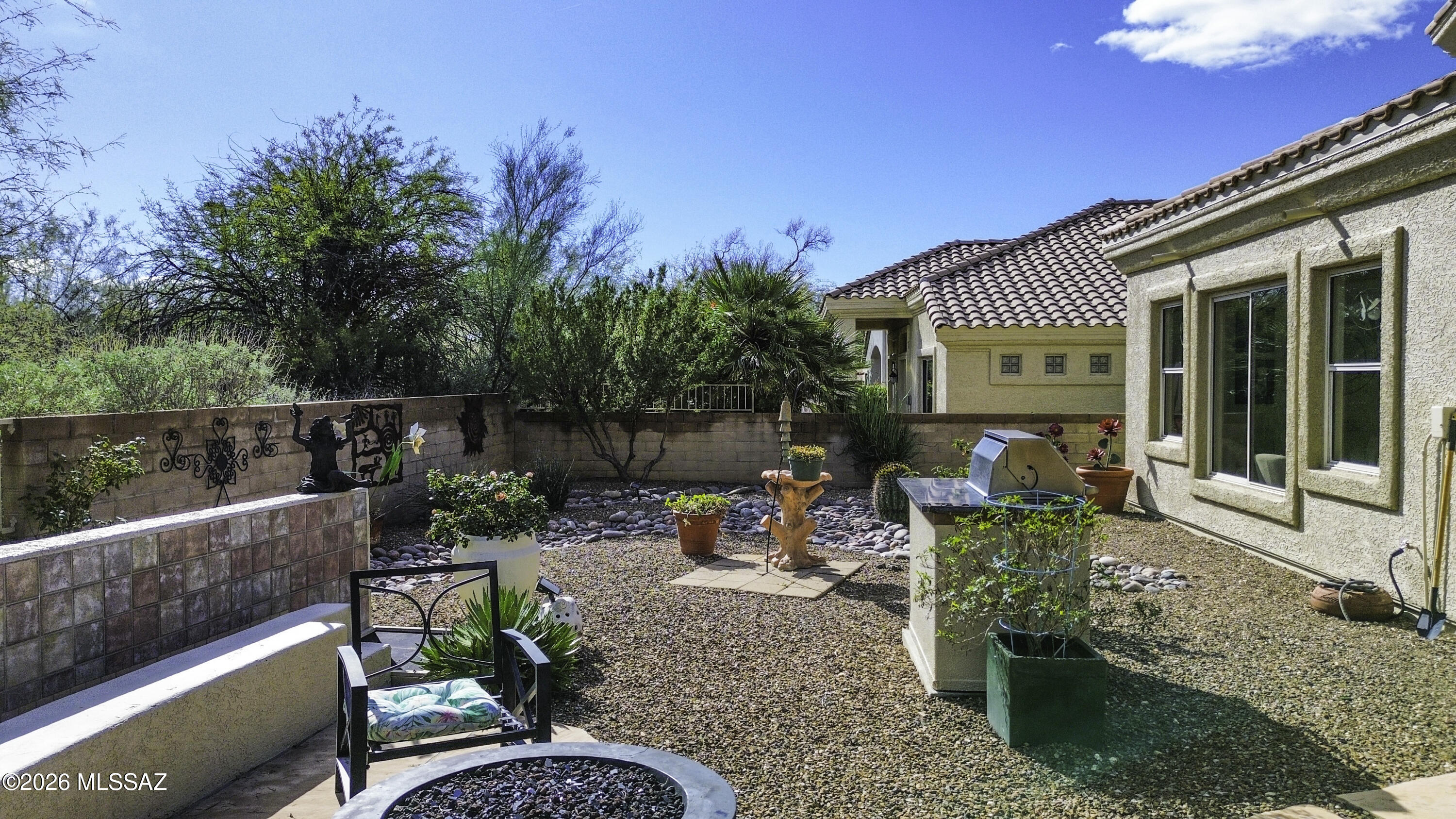 5202 Spring View Drive Tucson, AZ 85749 - Photo 40 of 49 a view of a patio with table and chairs potted plants with wooden fence
