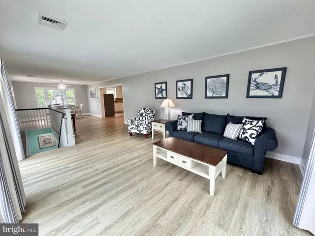 a kitchen with stainless steel appliances granite countertop white cabinets a sink a stove a microwave and wooden floors