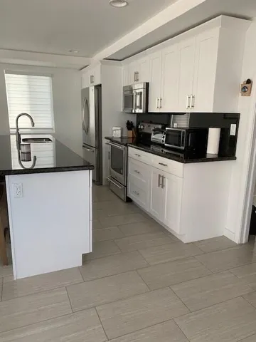 a kitchen with stainless steel appliances a sink a stove a microwave a sink a refrigerator and cabinets