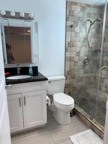 a bathroom with a granite countertop toilet sink and mirror