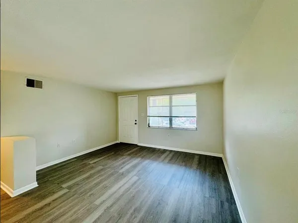 an empty room with wooden floor and windows
