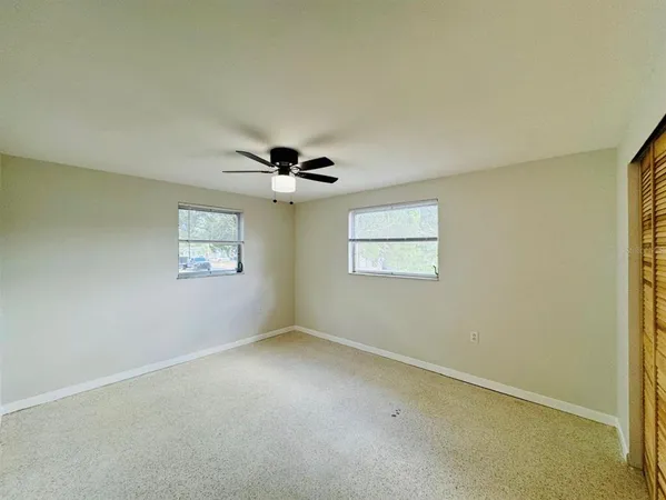 an empty room with a window and a ceiling fan